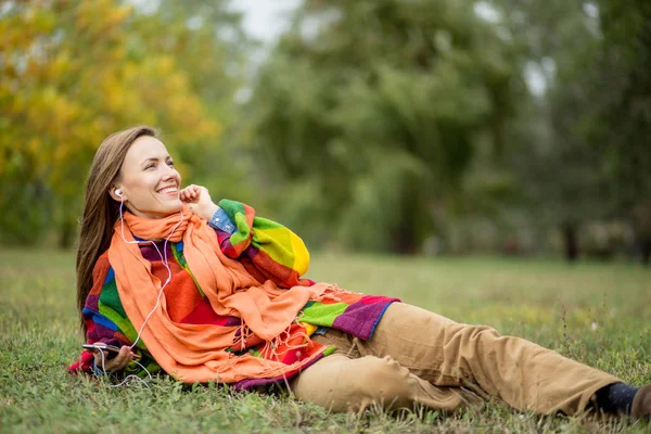 Mooie vrouw in herfst park ontspannen luisteren naar muziek — Stockfoto