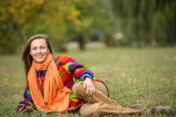 Красивая женщина в осеннем парке расслабляется, слушая музыку — стоковое фото