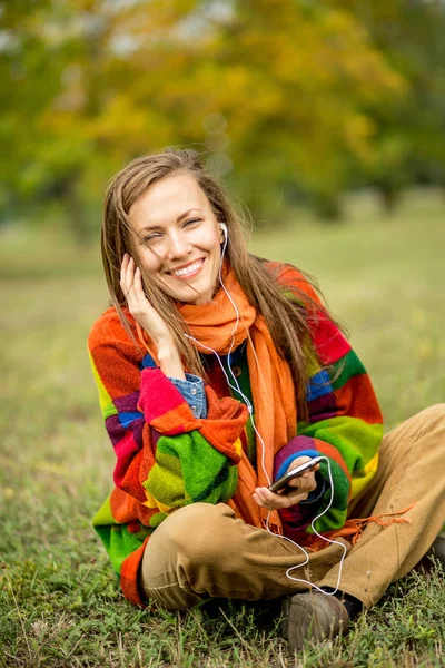 Mooie vrouw in herfst park ontspannen luisteren naar muziek — Stockfoto