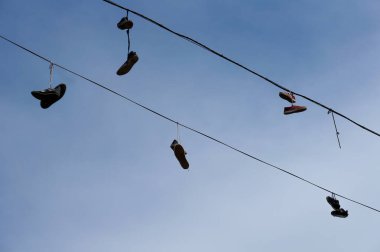 Gün batımında kabloda sallanan ayakkabı siluetleri