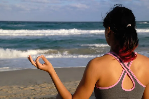 Giovane donna che pratica yoga sulla spiaggia Immagine Stock
