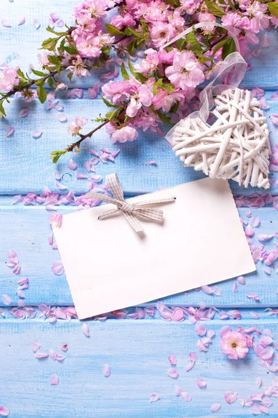 Sakura bloemen, decoratieve hart en lege tag op blauwe houten b — Stockfoto