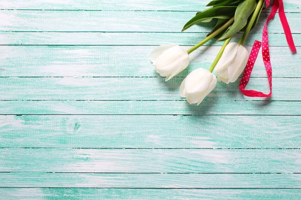 Drie witte tulpen op turquoise houten planken. — Stockfoto