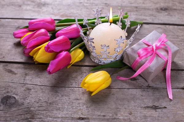 Яркие весенние тюльпаны, свечи и коробка с подарком — стоковое фото