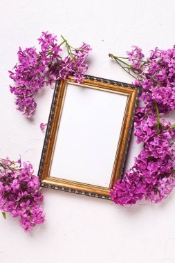 Taze leylak çiçekler ve gri dokulu arka plan üzerinde boş çerçeve.