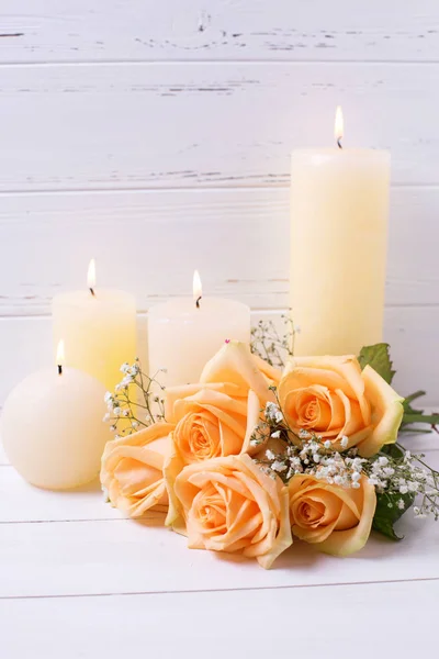 Pfirsichfarbene Rosen und brennende Kerzen — Stockfoto