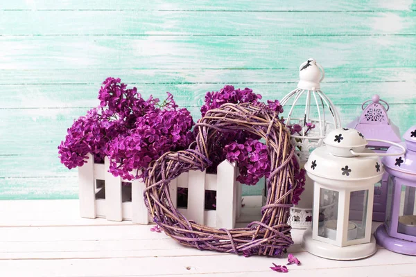 Čerstvé fialovými květy, ozdobné srdce a lucerny na bílou wo — Stock fotografie