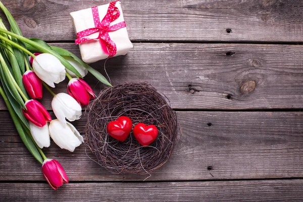 Petits coeurs rouges décoratifs dans le nid, tulipes printanières lumineuses — Photo