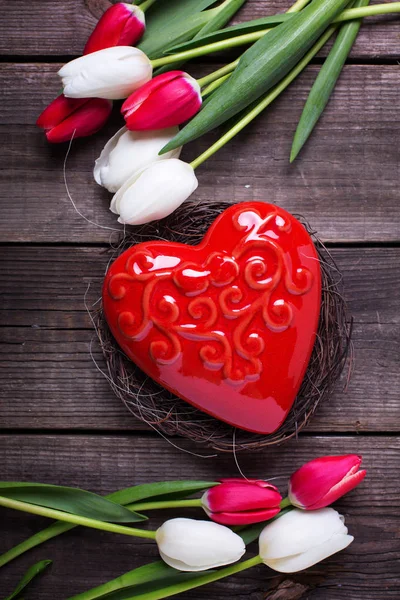 Coração vermelho decorativo em ninho e tulipas de primavera brilhantes — Fotografia de Stock