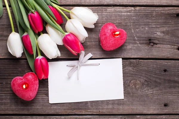 Dwie czerwone świece i brigh tulipany — Zdjęcie stockowe