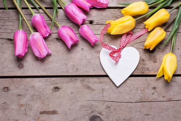 Coração branco decorativo e tulipas brilhantes — Fotografia de Stock
