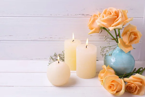 Hořící svíčky a broskvové barvy růží — Stock fotografie