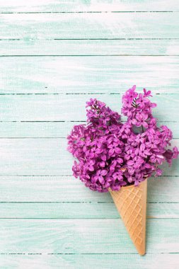 Gözleme koni turkuaz ahşap zemin üzerine taze leylak çiçeklenir. Dikey görüntü. Metin için yer.