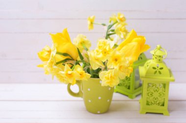 Parlak sarı bahar nergis veya nergis çiçek yeşil Kupası ve hafif ahşap zemin üzerine dekoratif Yeşil Fener. Seçici odak. Paskalya arka plan.