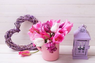 Pembe bahar lale çiçekleri pembe Kupası, Menekşe dekoratif kalp ve fener Beyaz ahşap zemin üzerinde. Seçici odak. 