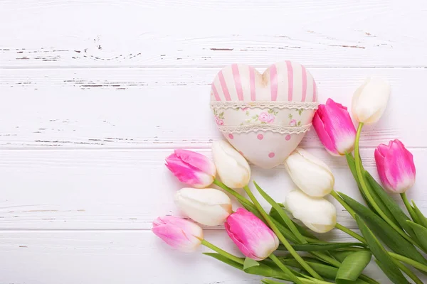 粉色和白色郁金香花和白色的木制背景上的装饰心 选择性的焦点 文本的地方 — 图库照片