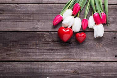 İki kırmızı dekoratif kalp ve parlak Lale çiçek ahşap arka plan üzerinde. Düz yatıyordu.