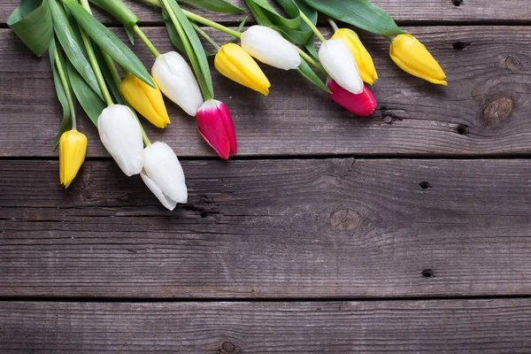 Parlak sarı, pembe ve beyaz laleler vintage ahşap zemin üzerinde. Düz yatıyordu.