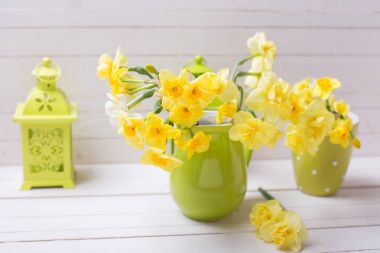 Yeşil vazo ve dekoratif Yeşil Fener Beyaz ahşap zemin üzerine sarı bahar nergis.