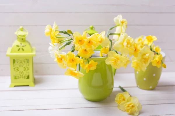 緑の花瓶の白い木製の背景に装飾的な緑提灯春に黄色の水仙 — ストック写真