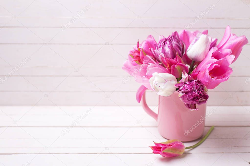 Bright pink  spring tulips flowers in pink  cup on white  wooden background. Selective focus. Spring  background. Place for text.