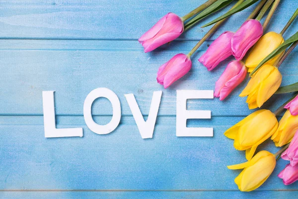 文字爱和粉红色 黄色和白色的花朵在蓝色的木制背景 爱的概念 — 图库照片