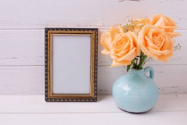 Beyaz ahşap zemin üzerinde mavi vazosu boş çerçeve ve gül çiçek.