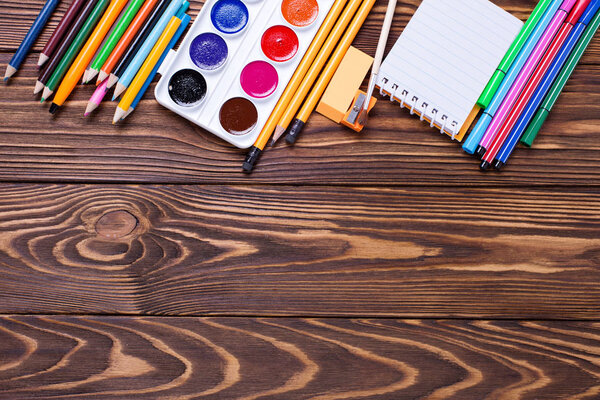 pencils, pen, note, eraser, paint on wooden background