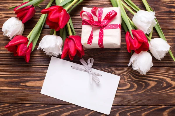 Verpakte doos met heden, lege tag en bloemen — Stockfoto