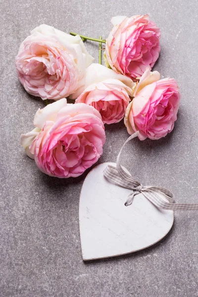 新鮮なピンクのバラとスレート グレーの背景に装飾的な白い心 選択と集中 トップ ビュー — ストック写真