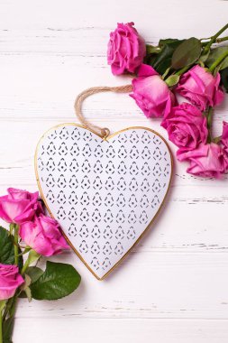 Dekoratif kalp ve çerçevelemek--dan pembe Gül çiçek Beyaz ahşap zemin üzerinde. Çiçekli natürmort. 