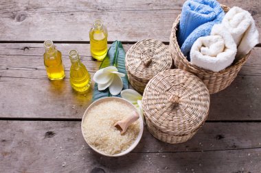 Mavi, sarı ve beyaz renklerde Spa ya da sağlık ayarı. Şişe wih temel aroma yağı, havlu, ahşap arka plan üzerinde deniz tuzu. Seçici odak.