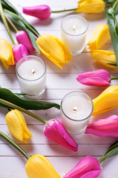 Leuchtend Rosa Und Gelbe Tulpenblumen Und Kerzen Auf Weißem Holzgrund — Stockfoto