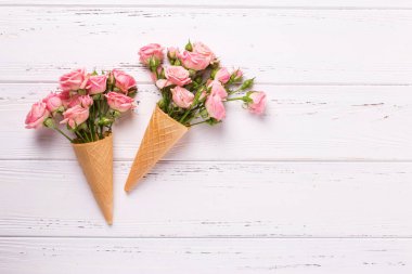 Beyaz ahşap zemin üzerinde taze pembe Gül çiçekli gözleme külah. Üstten Görünüm. Metin için yer. Seçici odak.