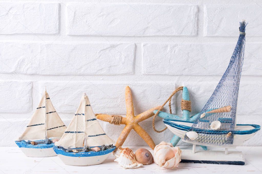 Coastal living background. Decorative boats, shells and sea stars  near by white brick wall. Selective focus. Place for text.