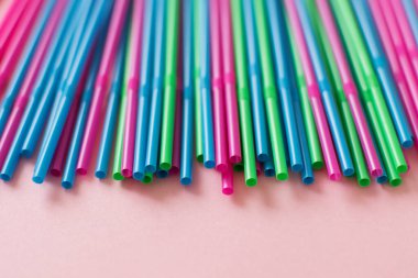 Pembe arka planda renkli pipetler. Plastik, yeniden kullanılabilir plastik, çevre dostu.