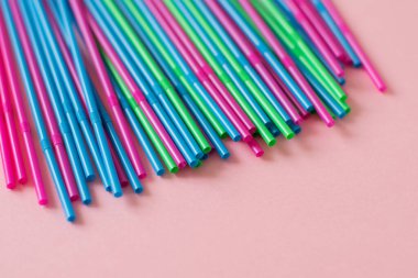Pembe arka planda renkli pipetler. Plastik, yeniden kullanılabilir plastik, çevre dostu.