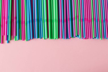 Pembe arka planda renkli pipetler. Plastik, yeniden kullanılabilir plastik, çevre dostu.
