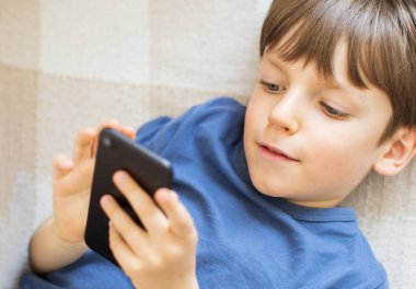 Küçük çocuk evde akıllı telefon izliyor. Ev işçiliği.