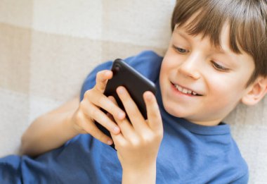 Küçük çocuk evde akıllı telefon izliyor. Ev işçiliği.
