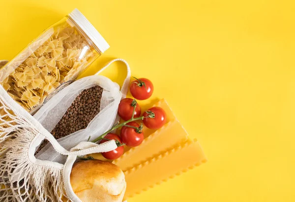 Food items in reusable string bag on yellow background. Delivery concept.