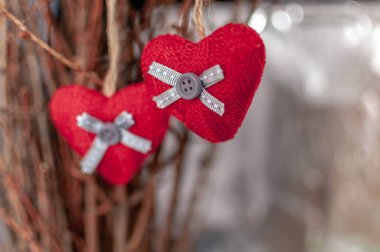 Bir dalda asılı iki örme kalp. Aşk sembolü ve Sevgililer günü kutlamaları. Tonda foto