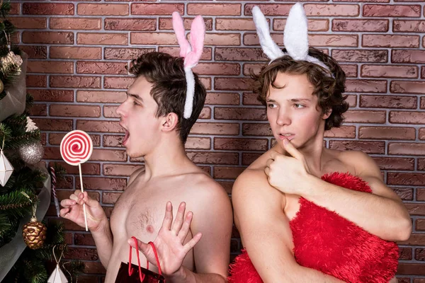 Два веселых парня в костюмах, празднующих Рождество за кирпичной стеной — стоковое фото