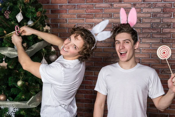 Dva legrační kluci v oblecích králíci slaví Vánoce přes cihlovou zeď — Stock fotografie