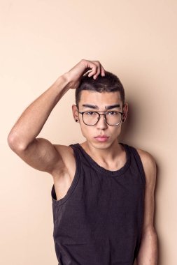 Gözlüklü genç seksi adam poz veriyor ve kameraya bakıyor.