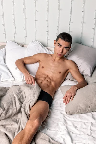Joven hombre guapo descansar en la cama. Sexy chico desnudo está descansando — Foto de Stock