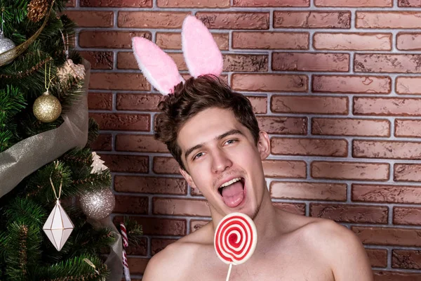 Fešák nahý chlap v obleku králík slaví Vánoce přes cihlovou zeď — Stock fotografie