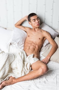 Genç yakışıklı adam yatakta dinleniyor. Seksi çıplak adam dinleniyor.
