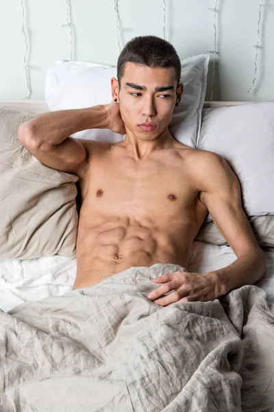 Joven hombre guapo descansar en la cama. Sexy chico desnudo está descansando — Foto de Stock