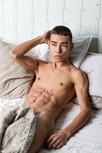 Joven hombre guapo descansar en la cama. Sexy chico desnudo está descansando — Foto de Stock